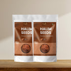 Two packages of Organic Halim Seeds on a wooden surface with a beige background
