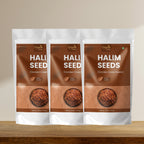 Three packages of Halim seeds on a wooden surface with a beige background